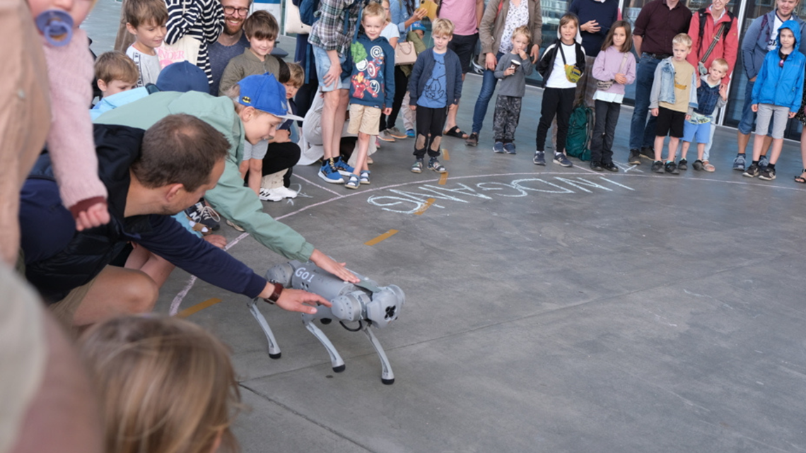 Mennesker danner en ring om en robot hund 